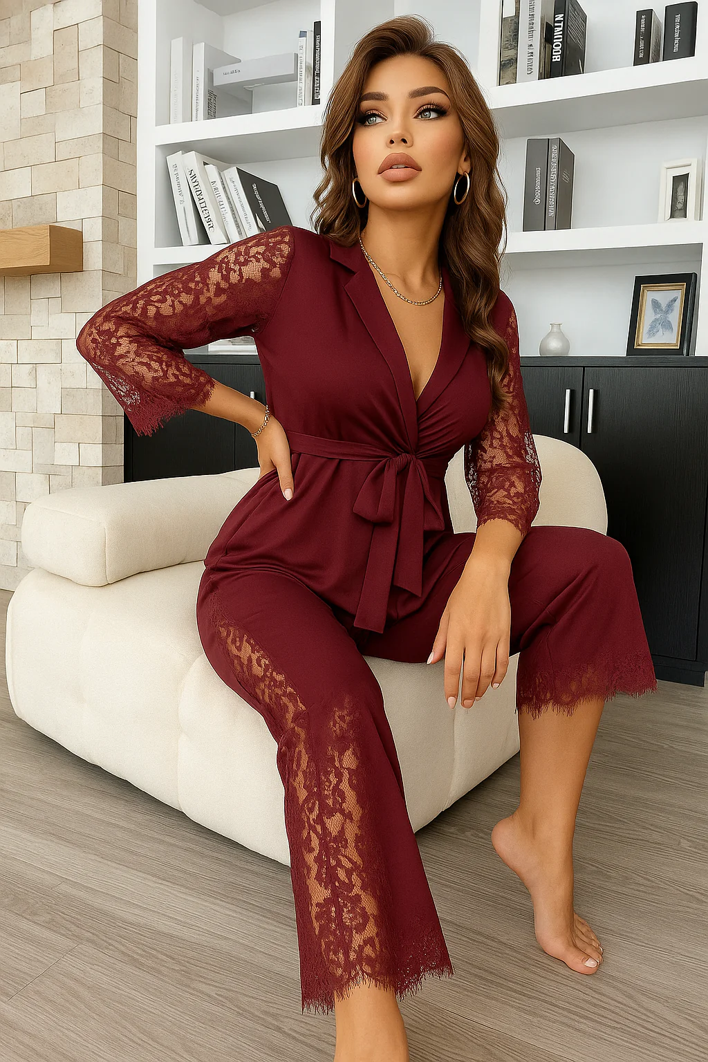 Woman in a maroon nigghtwear lace outfit sitting on a white chair in a room with shelves and books.