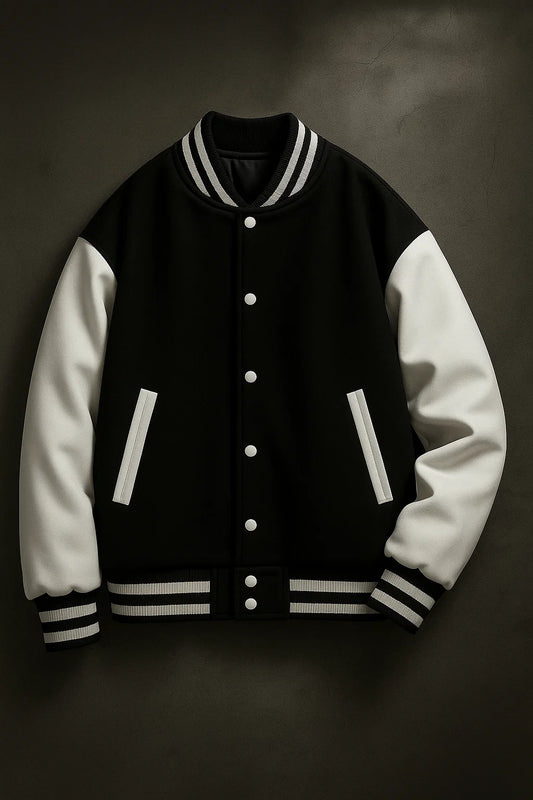Close-up of classic black varsity jacket with white contrast sleeves, snap buttons, and striped rib-knit trim.