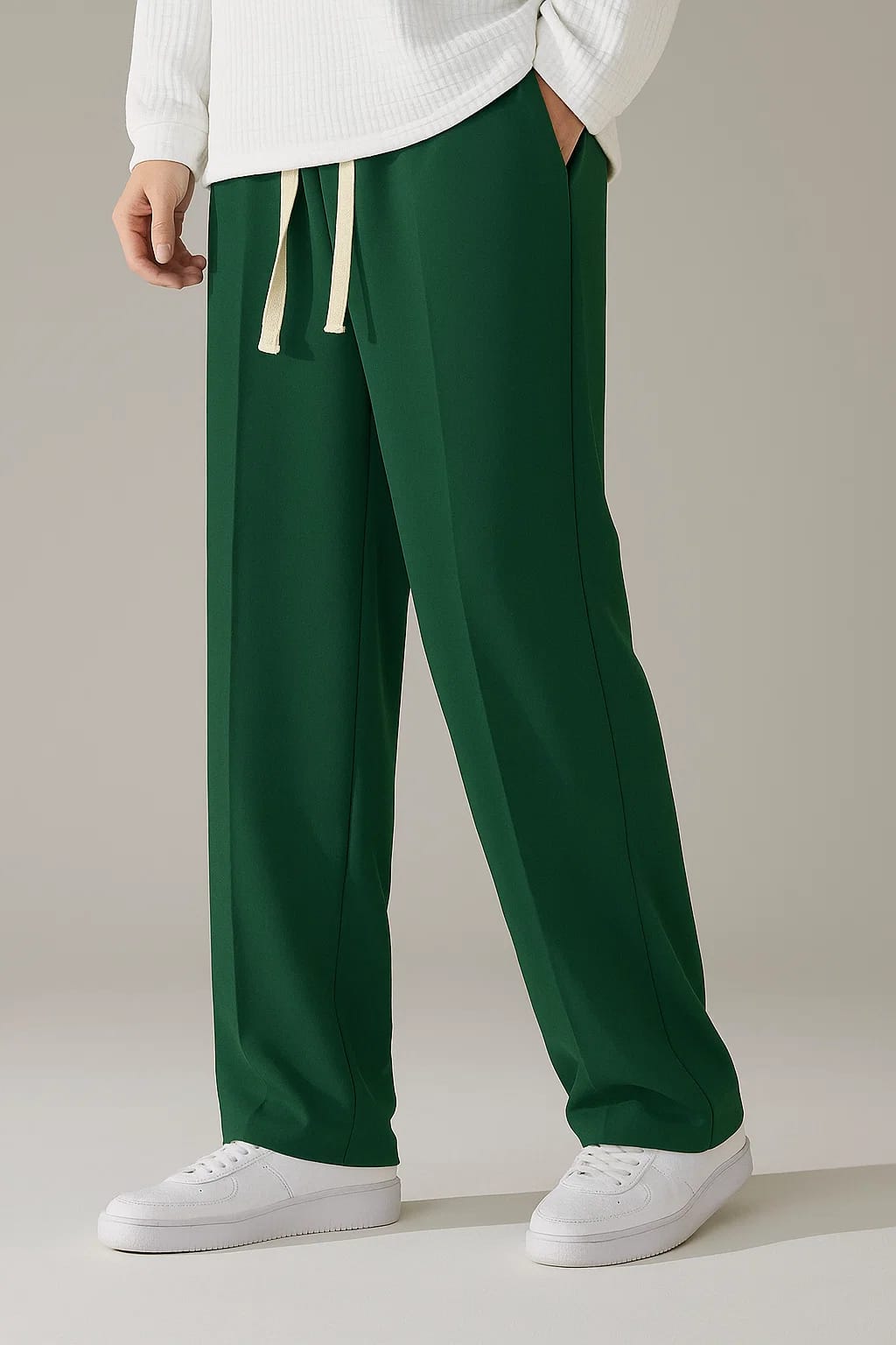 Men's relaxed baggy trousers in Forest Green with a single-line seam, styled with a white ribbed sweater and white sneakers.