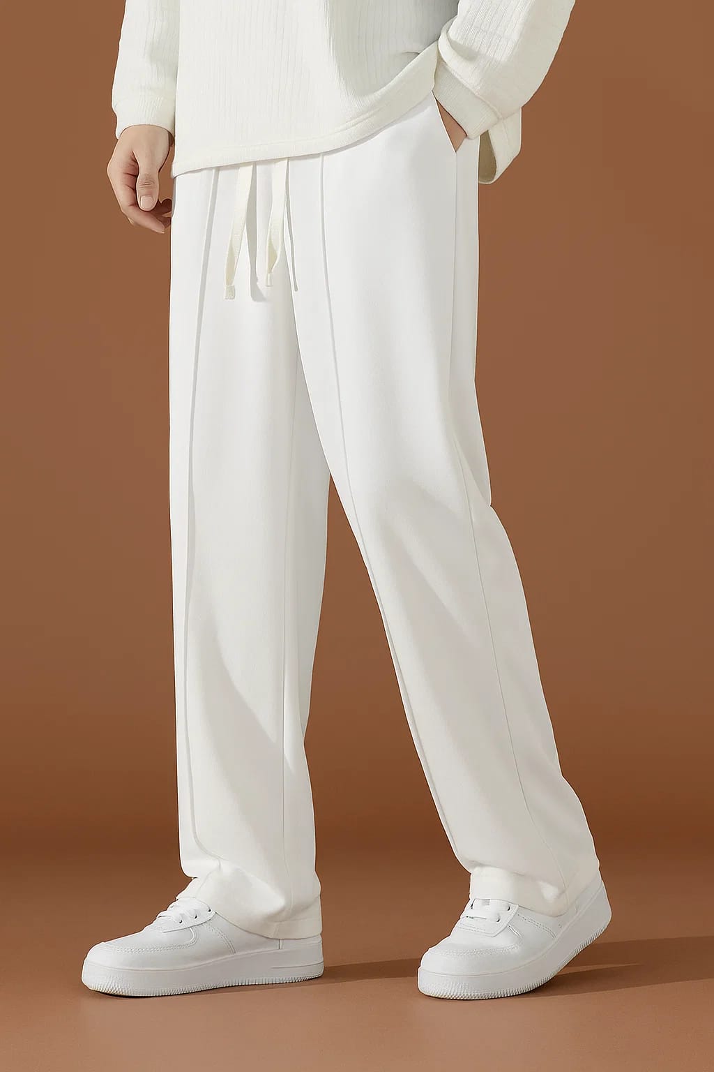 Men's crisp White baggy drawstring pants, featuring a center stitched line and styled with white sneakers.
