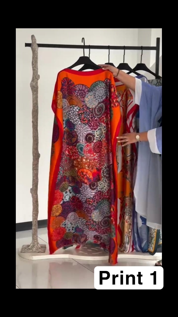 Vibrant multi-colored circular print kaftan with a bright orange border, displayed on a clothing rack 01