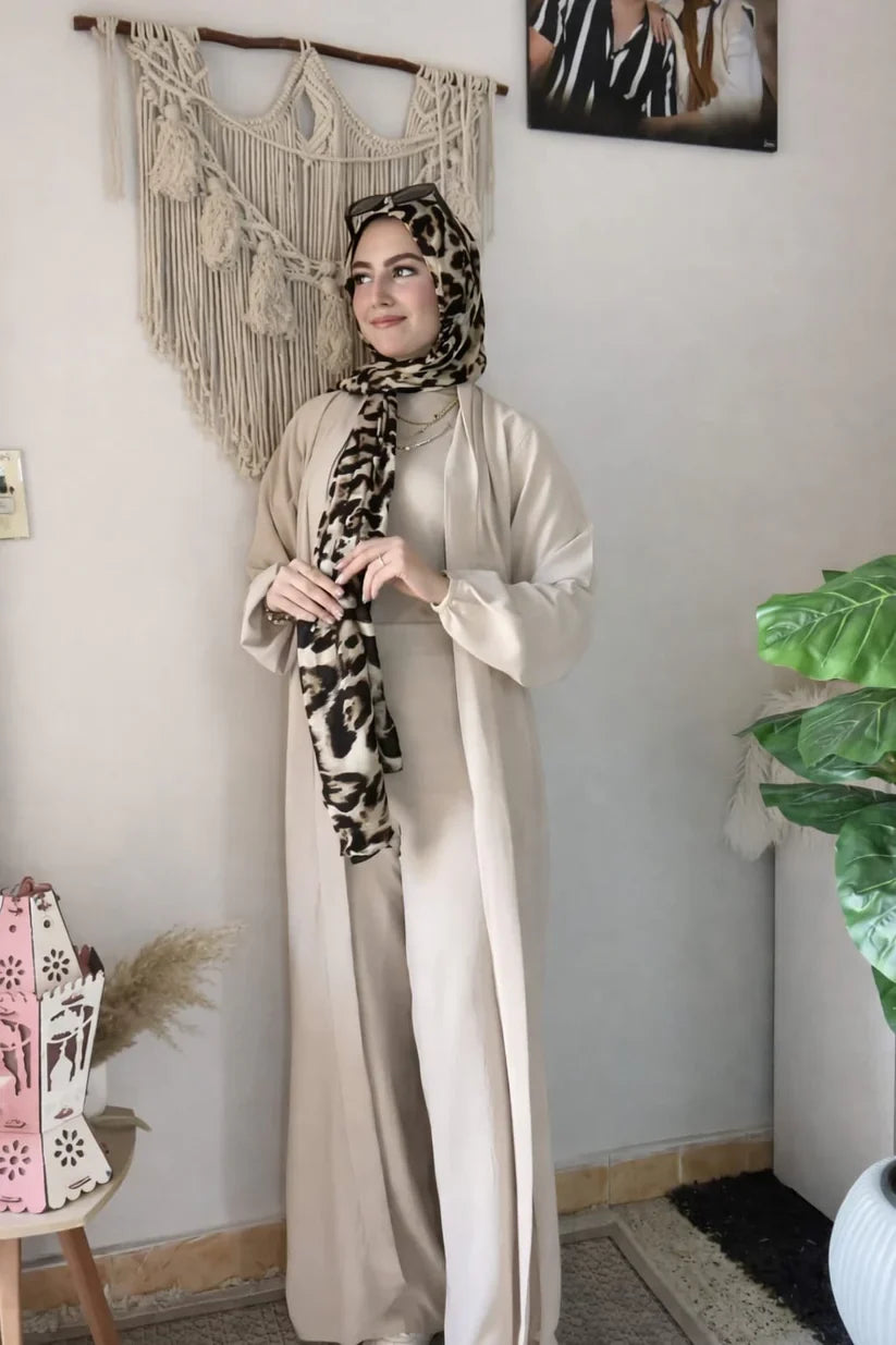 Woman wearing a chic beige three-piece modest ensemble with a long cardigan, wide-leg trousers, and a bold leopard print hijab 05